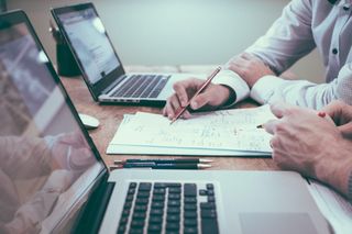 Candidate reviewing notes beside a laptop, suggesting structured hiring-assessment preparation