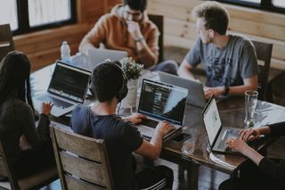Small team collaborating around laptops in a bright workspace